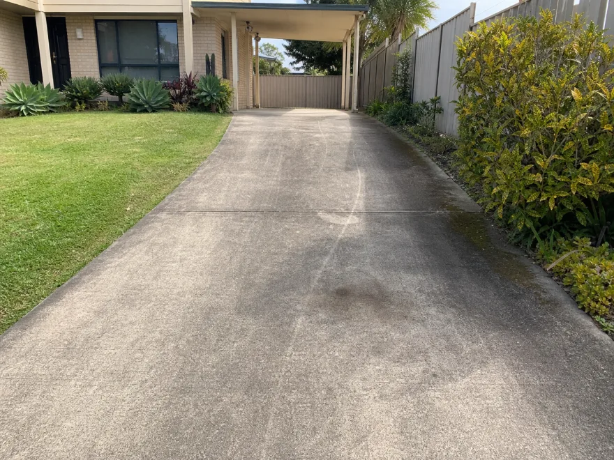 Same concrete Brisbane driveway before pressure cleaning, with dirt and dark staining