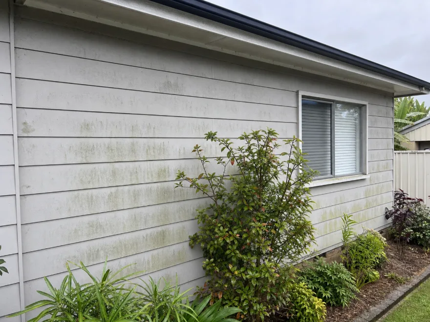 Same rendered house before washing, streaked with mould and grime