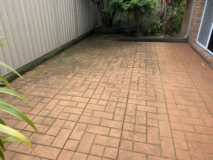 Same Brisbane brick-paver courtyard before pressure cleaning, with ground-in grime and algae